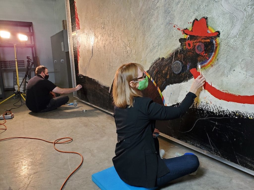 Two art conservators restoring a work of abstract art.