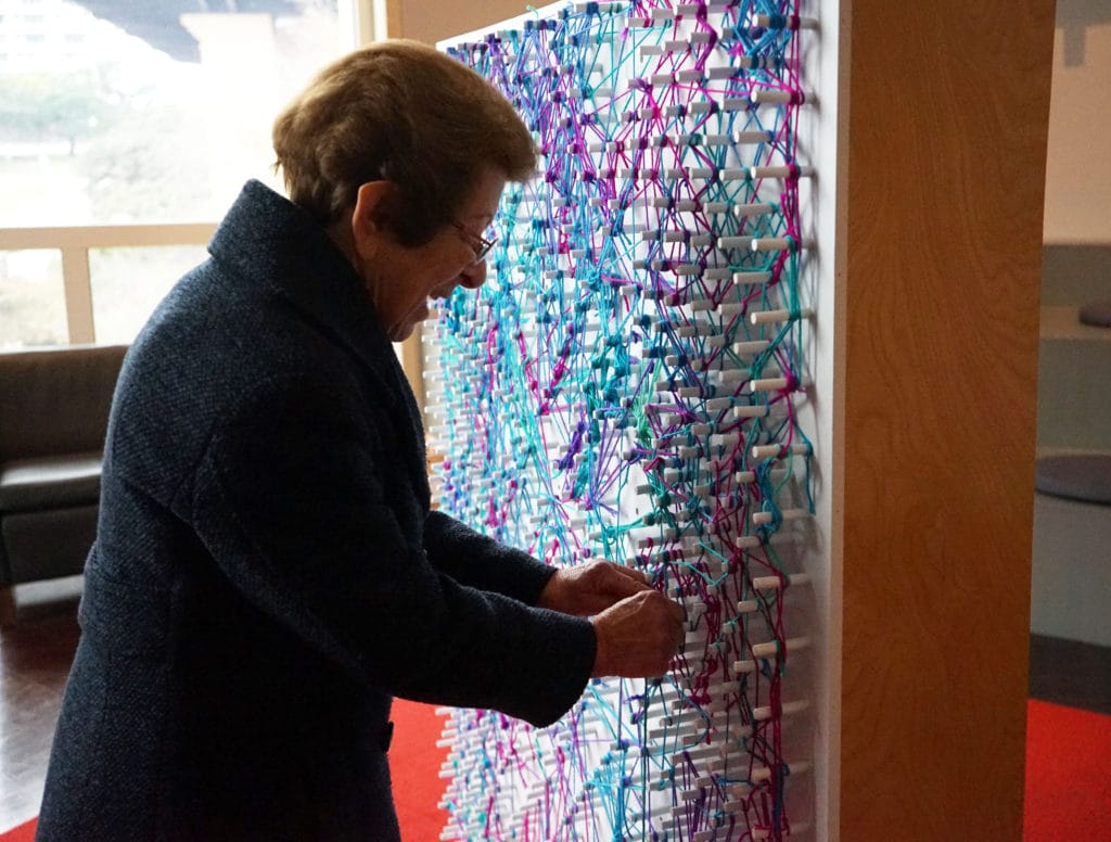 an elderly woman woman working on a weaving project