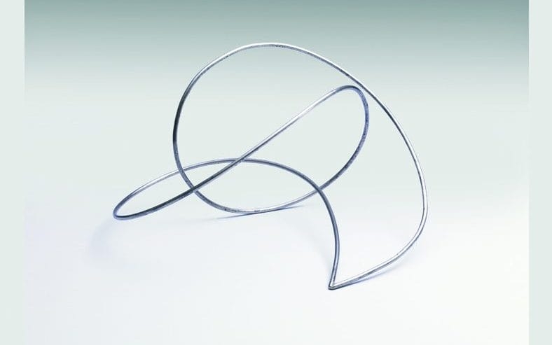 A metal sculpture consisting of one continuous loops that arches over itself multiple times.