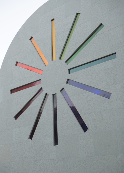 View of the west exterior wall of Ellsworth Kelly's Austin; twelve slim rainbow colored stained glass rectangles are arranged as a star burst.