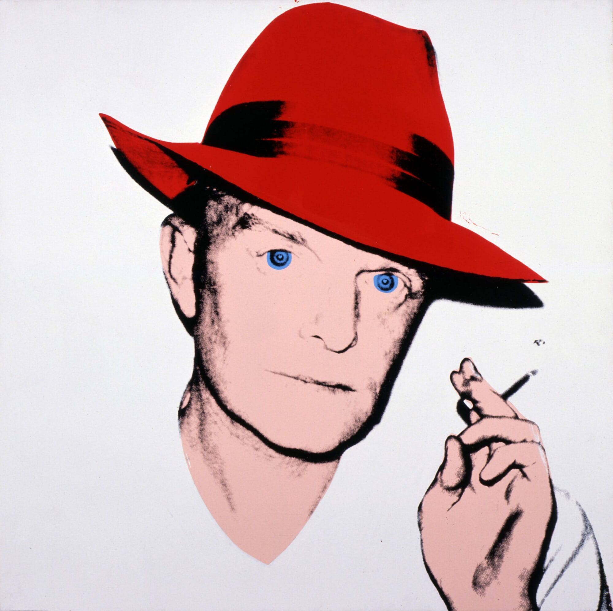 Portrait of Truman Capote, depicted from the shoulders up. He looks at the viewer with a neutral expression, holding up a cigarette in one hand. He is wearing a red fedora.