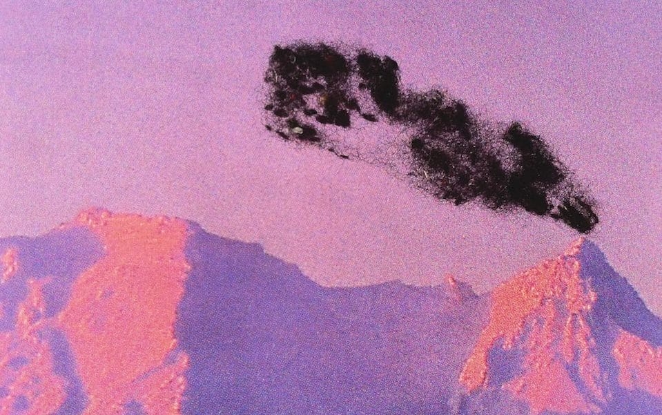 Purple and pink mountains with black smoke coming out of the top of one mountain.