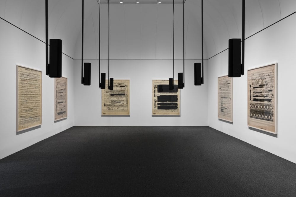 Six large screenprints on three gallery walls. Speakers hang from the ceiling.