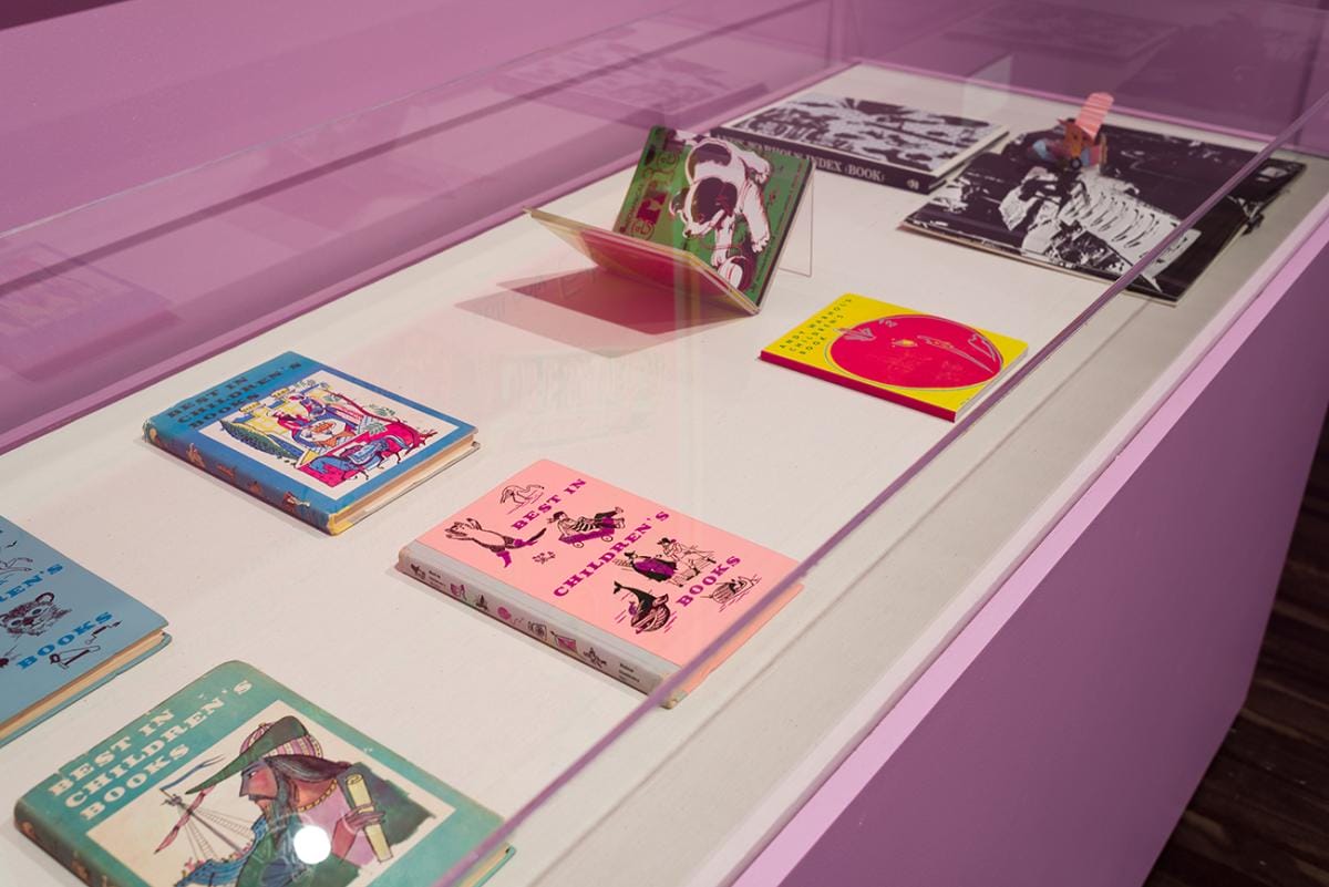 Printed children's books with bright colored illustrations on the covers in a display case.