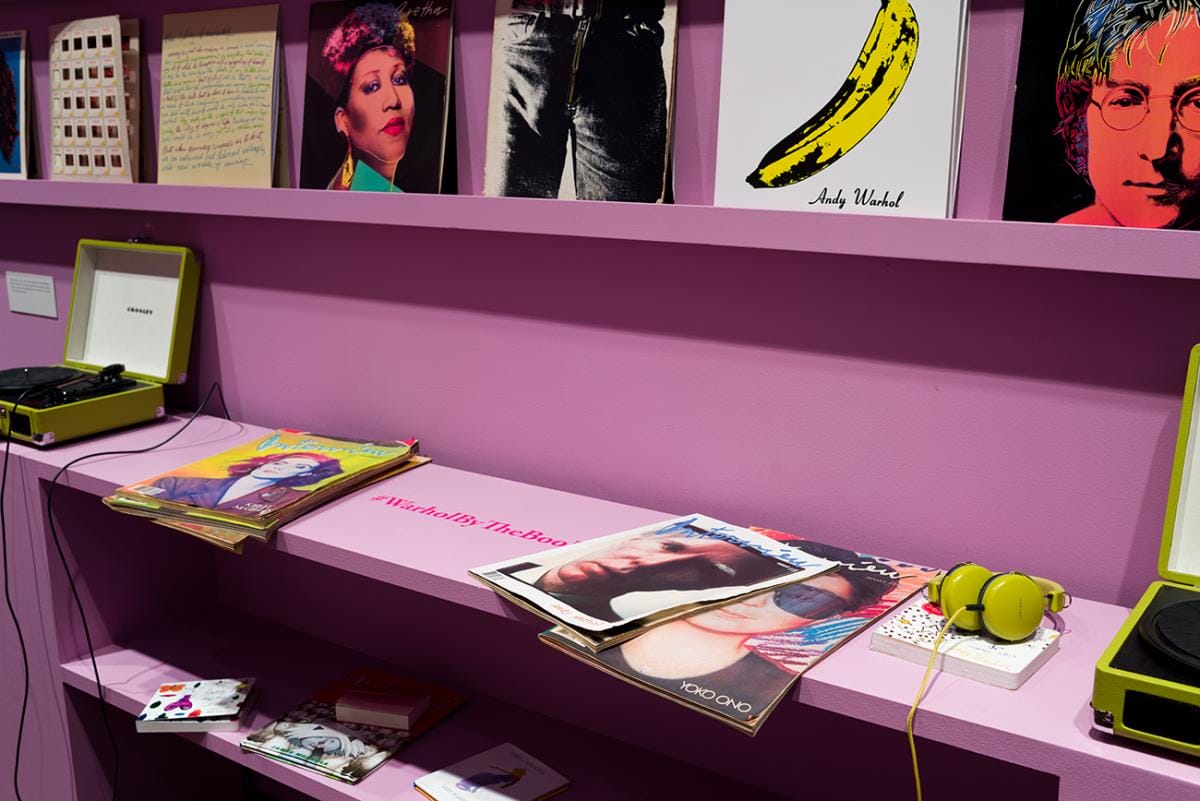 Vinyl album covers displayed on a shelf above a book case with several magazines displayed on top in the resource room.