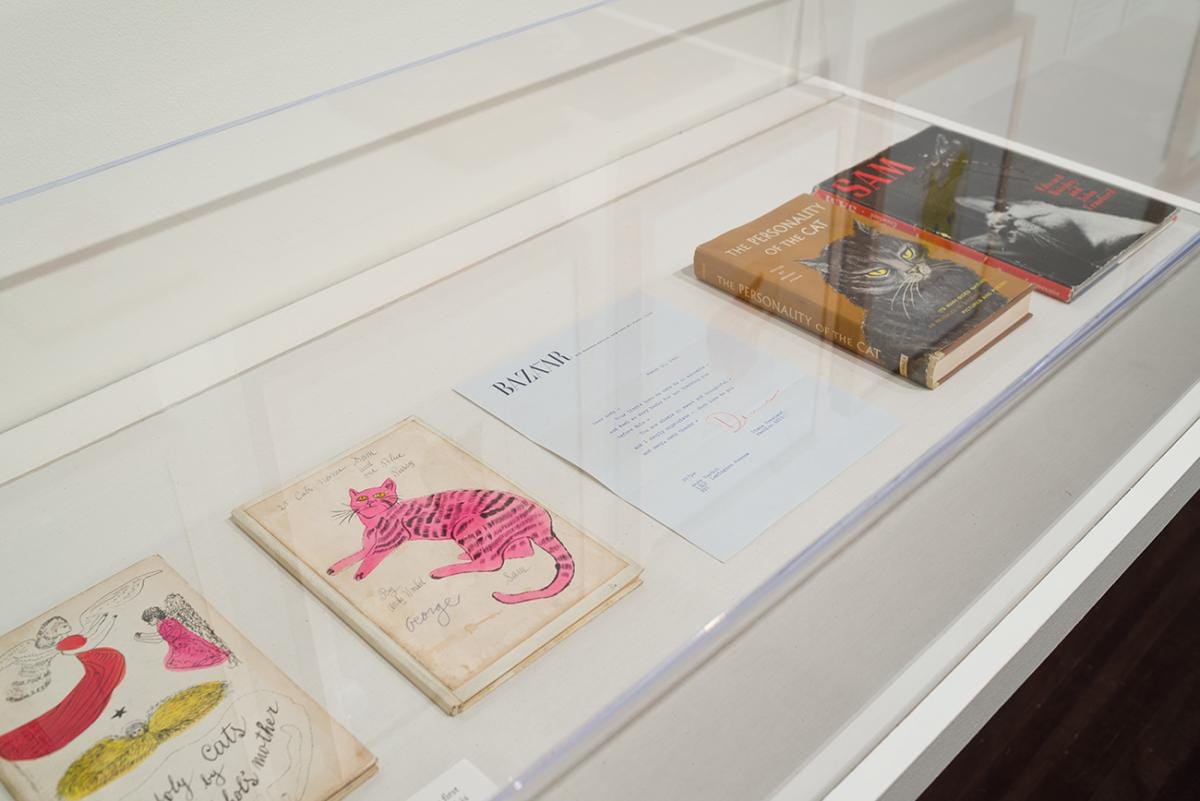 Printed books featuring illustrations of cats and a typed letter in a case.