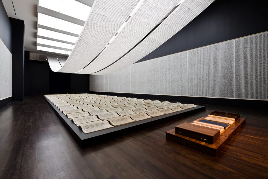 Large Chinese scrolls posted on the walls and draped from the ceiling. Open books are laid out in the center of the floor.