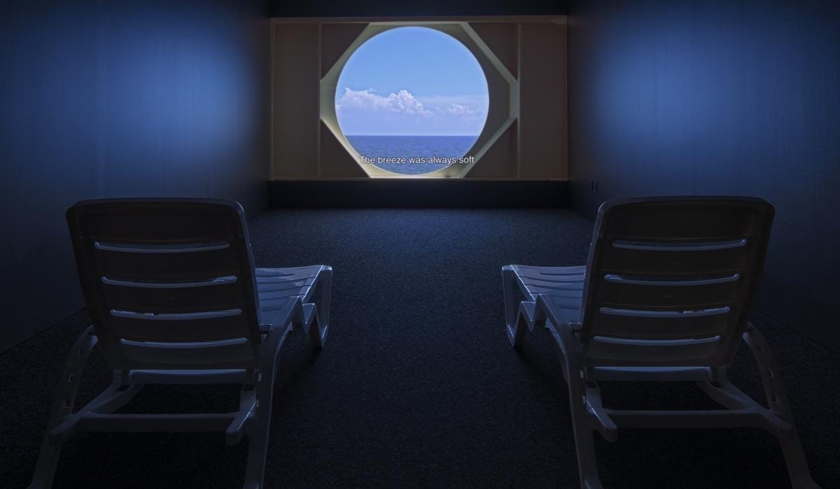 Two chairs in a room beside a large window, providing a scenic view of the ocean outside.