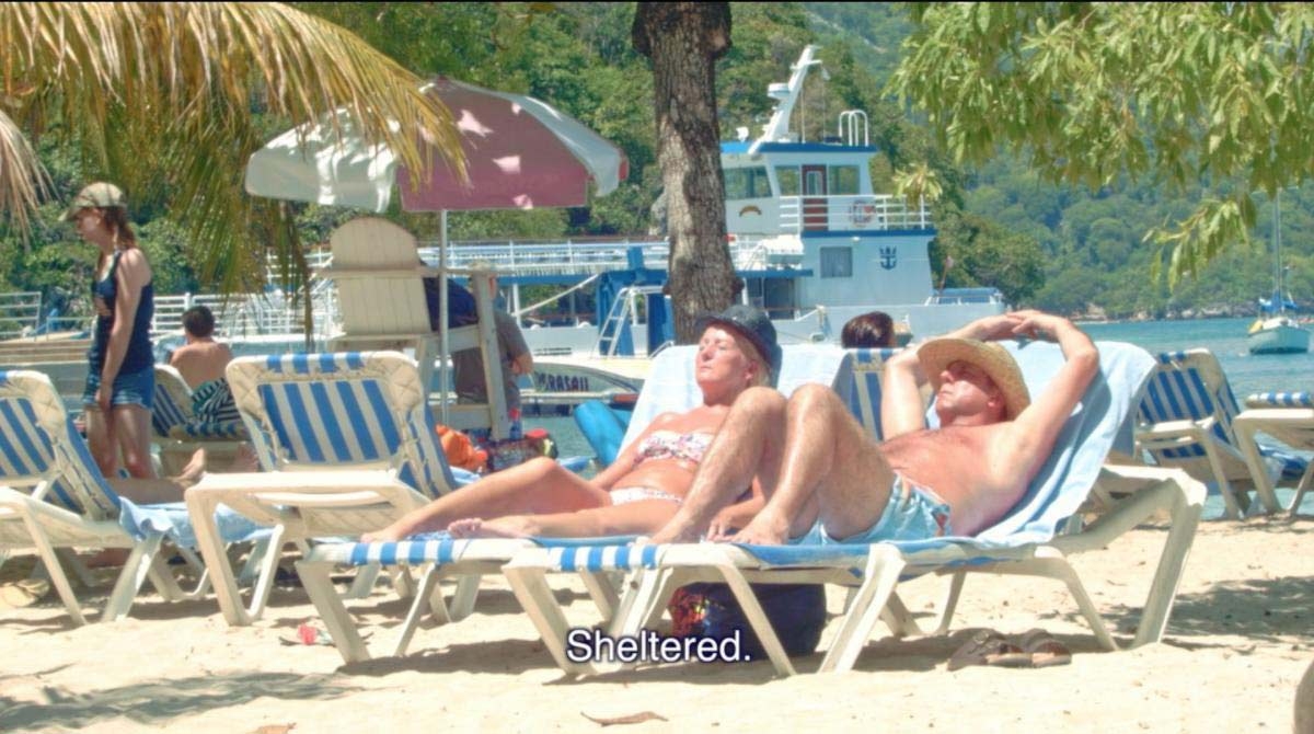 Two individuals relax on the beach, basking in the sun and enjoying the tranquil ocean view. Thre word 