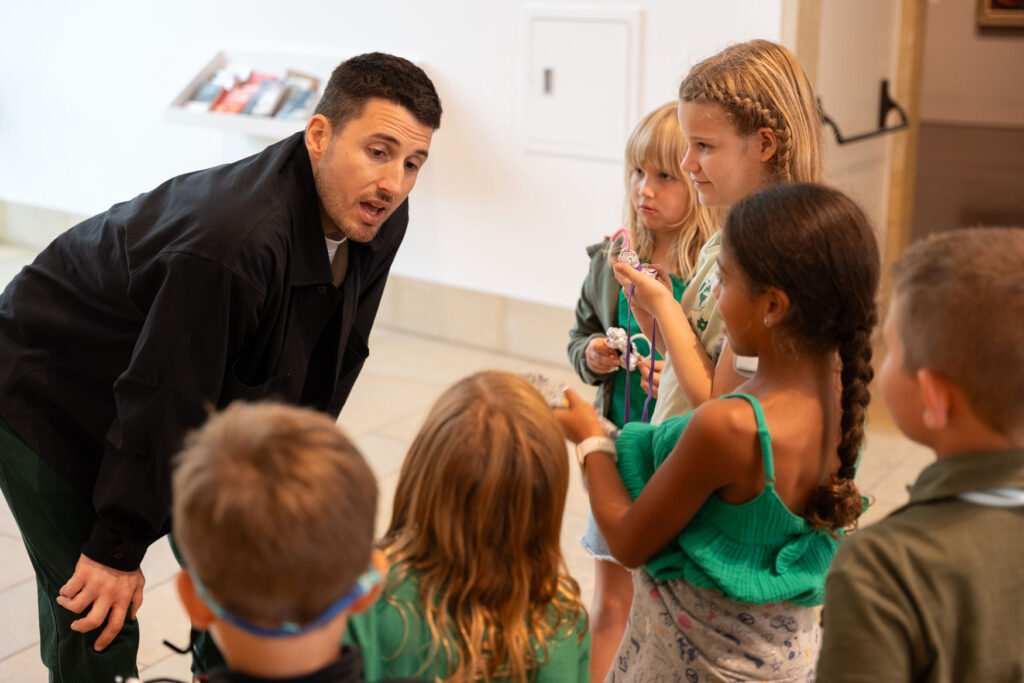 A K-12 teacher speaking with students of his class in the museum galleries.