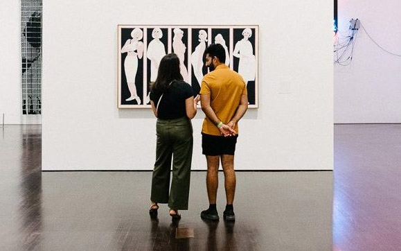 Couple standing and conversing in front of an artwork in the galleries